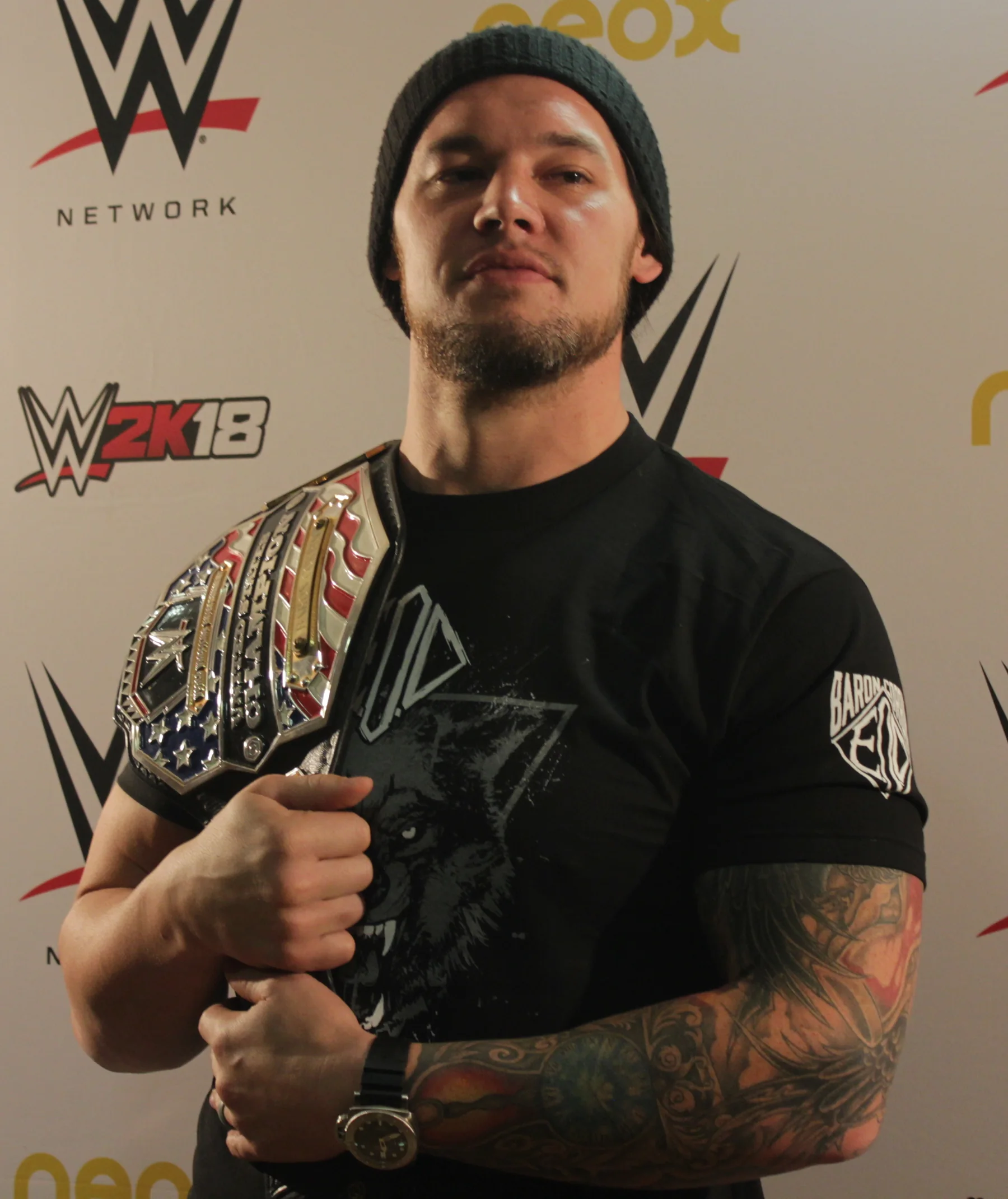 Baron Corbin posing with the WWE United States Championship at a media event
